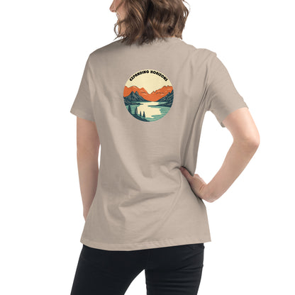 Woman wearing a stone relaxed t-shirt featuring a scenic mountain and lake design with 'Expanding Horizons' text