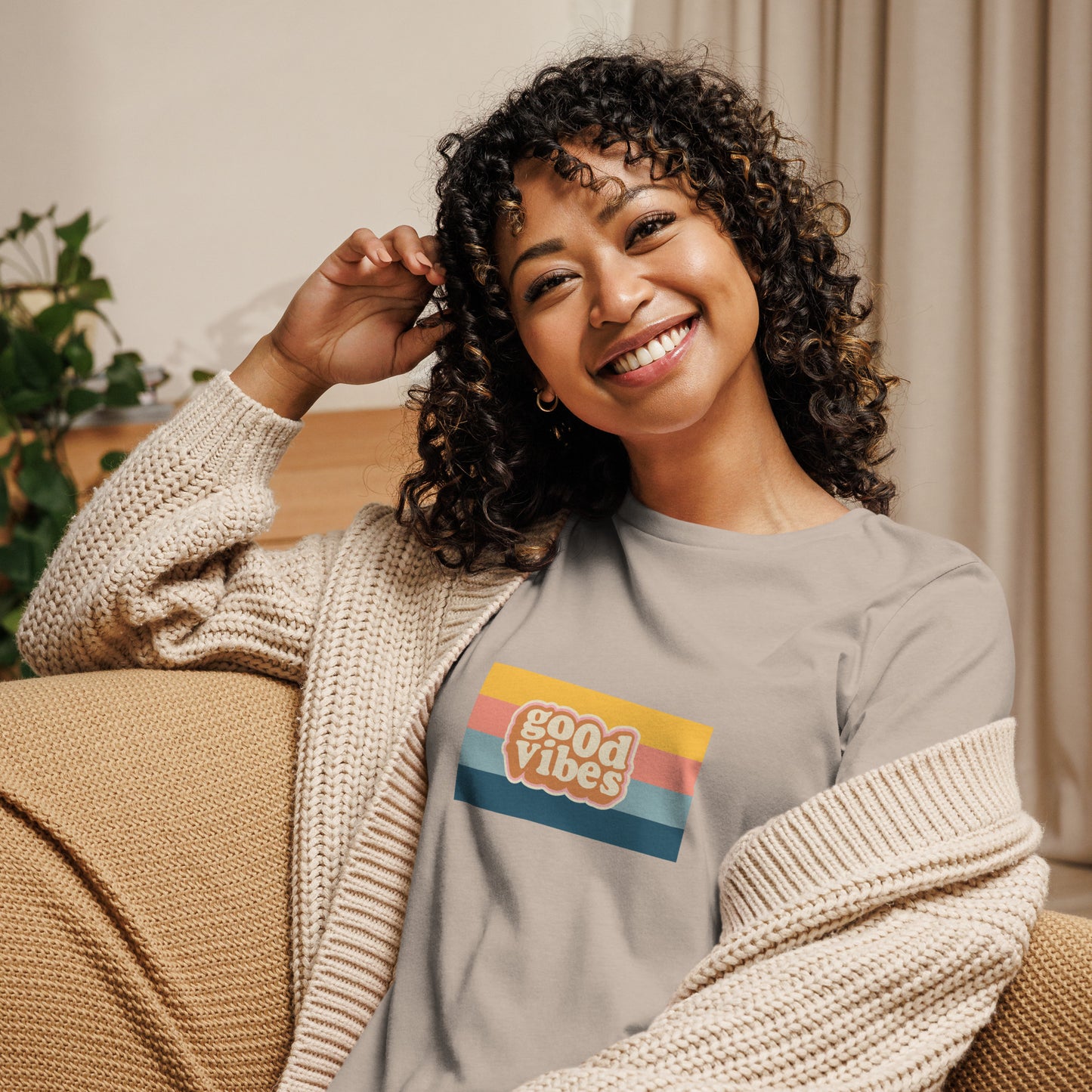 Woman smiling in a heather stone relaxed t-shirt with colorful 'Good Vibes' graphic