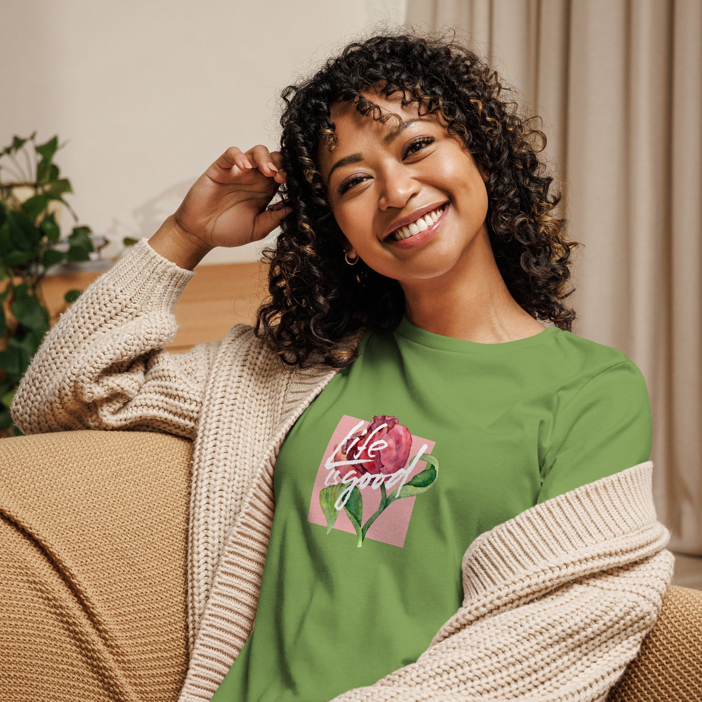 Woman smiling in a leaf green relaxed t-shirt with colorful 'Life in Bloom' floral design