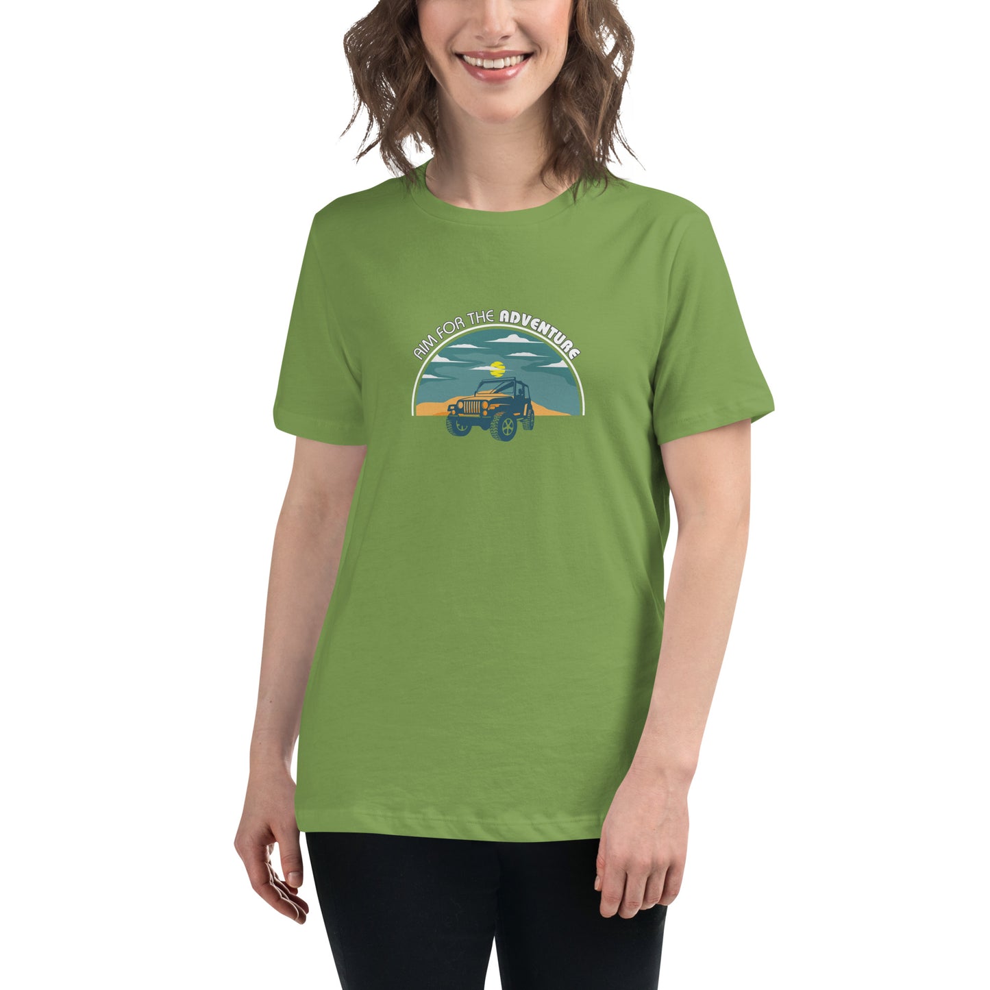 Woman smiling in a leaf green relaxed t-shirt with 'Aim for the Adventure' and a vintage camper graphic