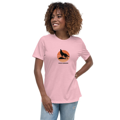 Woman wearing a pink bravery-themed relaxed t-shirt with a wolf graphic and 'Stealthy Wanderer' text in a sunset backdrop