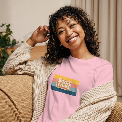 Woman smiling in a heather natural relaxed t-shirt with colorful 'Good Vibes' graphic