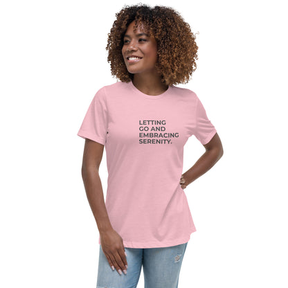 Woman wearing a pink relaxed tee with "Letting Go and Embracing Serenity" printed, available in various colors and sizes from S-3XL.