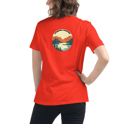 Woman wearing a poppy red relaxed t-shirt featuring a scenic mountain and lake design with 'Expanding Horizons' text