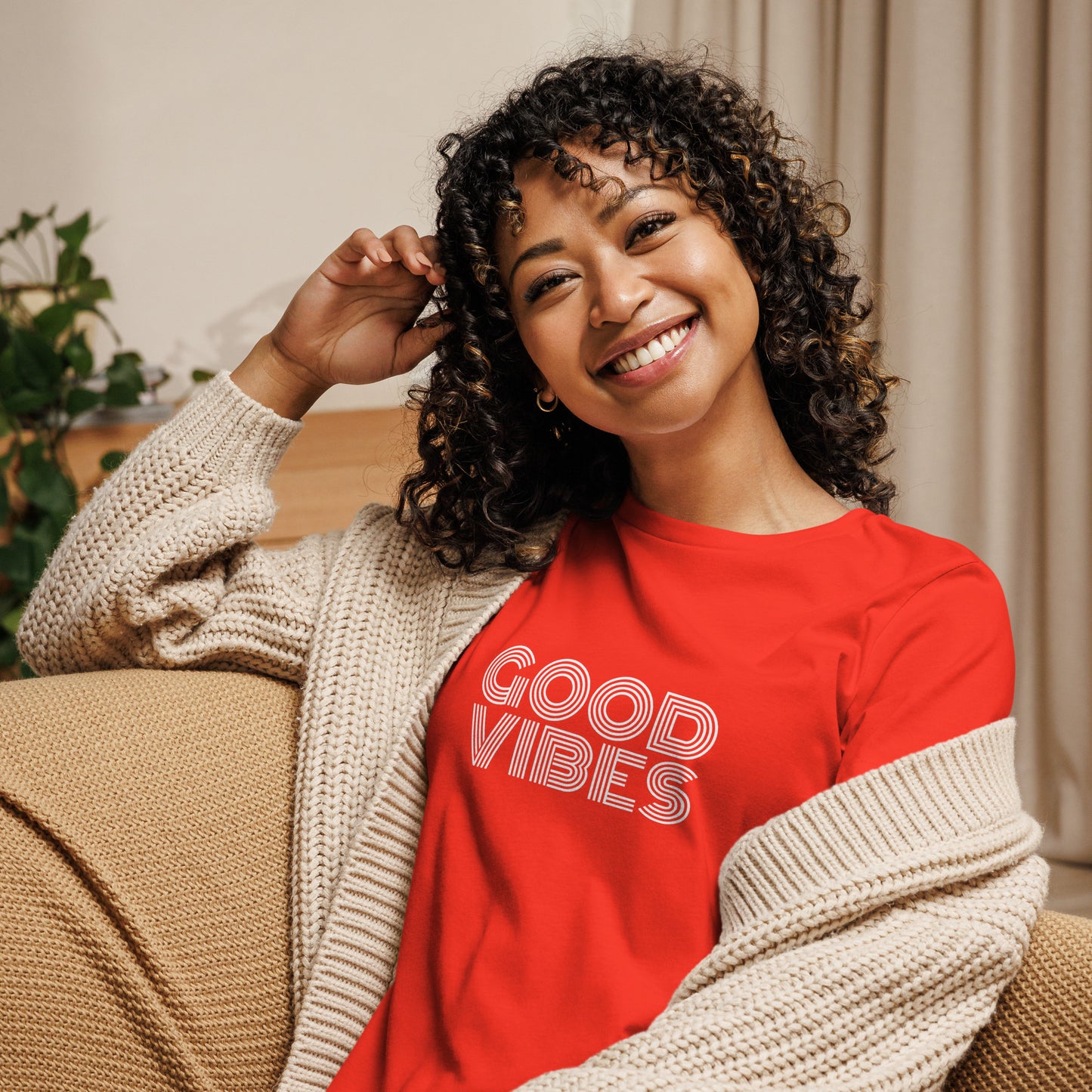 Woman smiling in a poppy red relaxed t-shirt with "Good Vibes" in white lettering, promoting a positive and cheerful style.