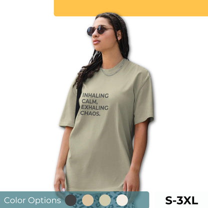 Woman wearing a faded oversized tee in various colors and sizes S-3XL, featuring the phrase "Inhaling Calm, Exhaling Chaos."