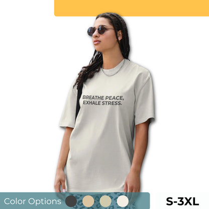 Woman wearing a faded oversized tee in various colors and sizes S-3XL, featuring the phrase "Breathe Peace, Exhale Stress."